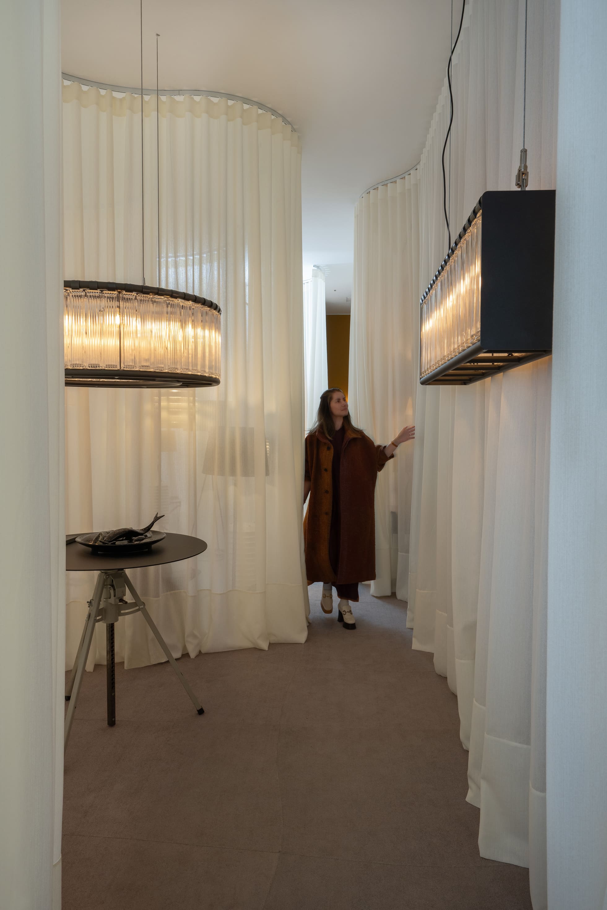 Ambiente da exposição Senderos com luminárias e cortinas translúcidas